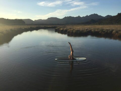 Yoga pose on paddle board on Kaitoke stream. Aotea Great Barrier Island