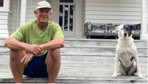 Derek Bell sat on deck with dog on Great Barrier Island